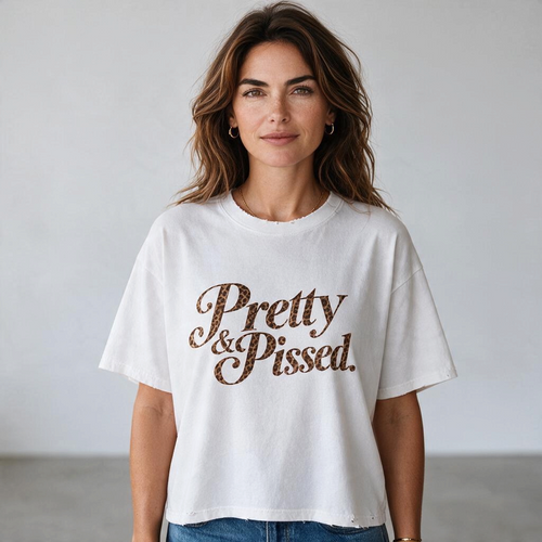 The Darling Outlaw white oversized cotton t-shirt with Pretty & Pissed leopard-print lettering and frayed edges.