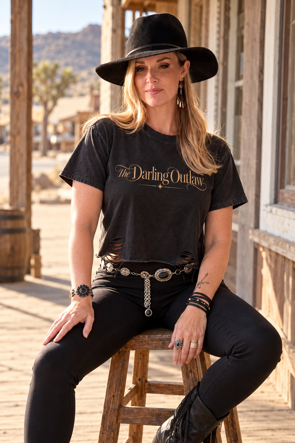 Black The Darling Outlaw distressed graphic tee with gold lettering and raw hem — product view 1