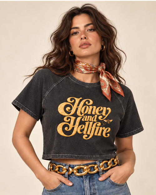 Model wearing The Darling Outlaw black cropped raglan tee with honey-gold lettering and a small bee graphic.